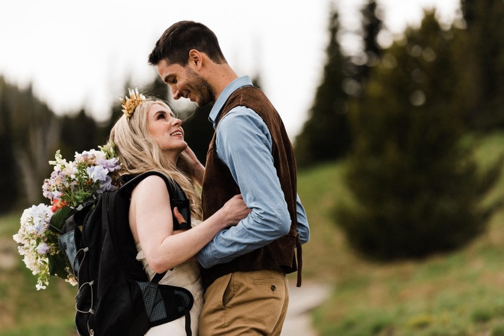 Bride wearing a backpack with her bouquet in it during an adventurous elopement in Mount Rainier National Park.