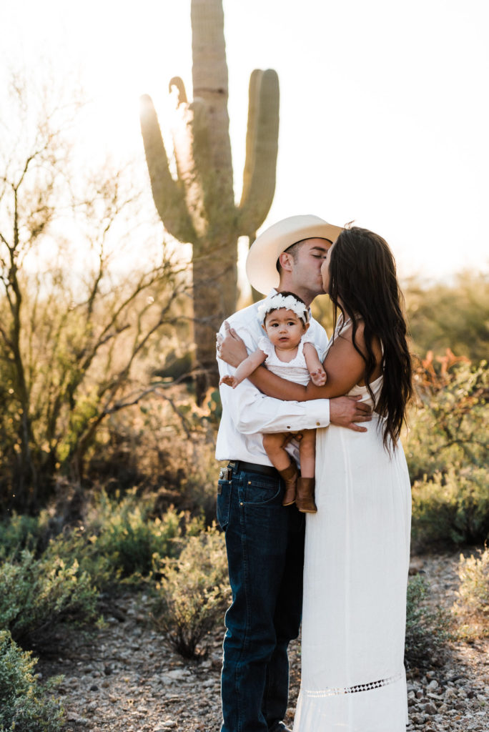Eloping couple with a child kissing in the desert photographed by an Arizona wedding photographer.
