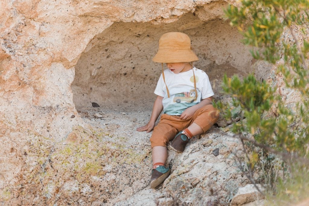 child in a sunhat taking a break during a summer hike