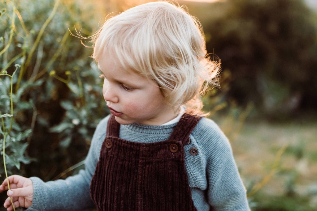 Child dressed in cute overalls during a hiking elopement with kids.