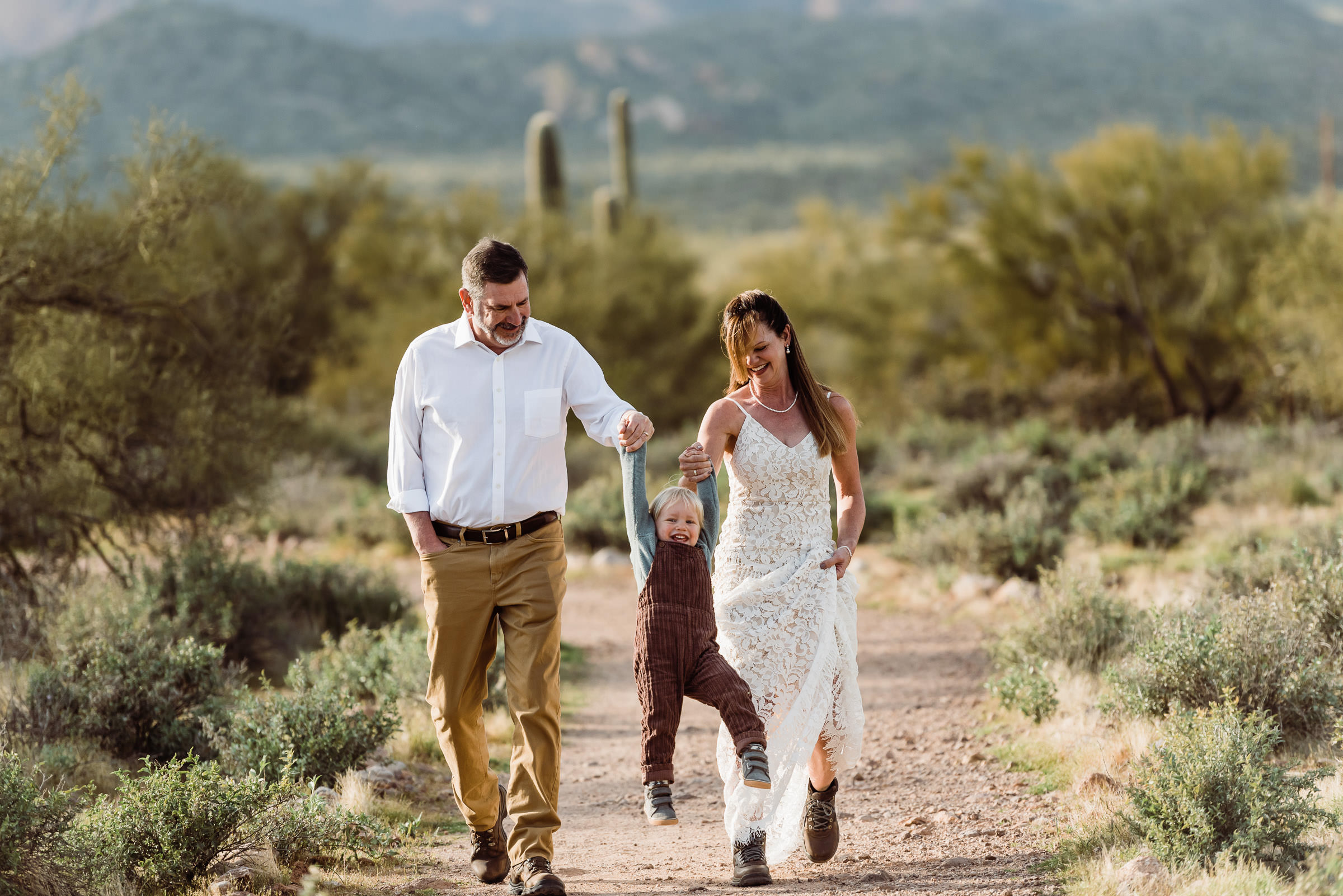 A couple walking through the desert with their child during their Arizona elopement