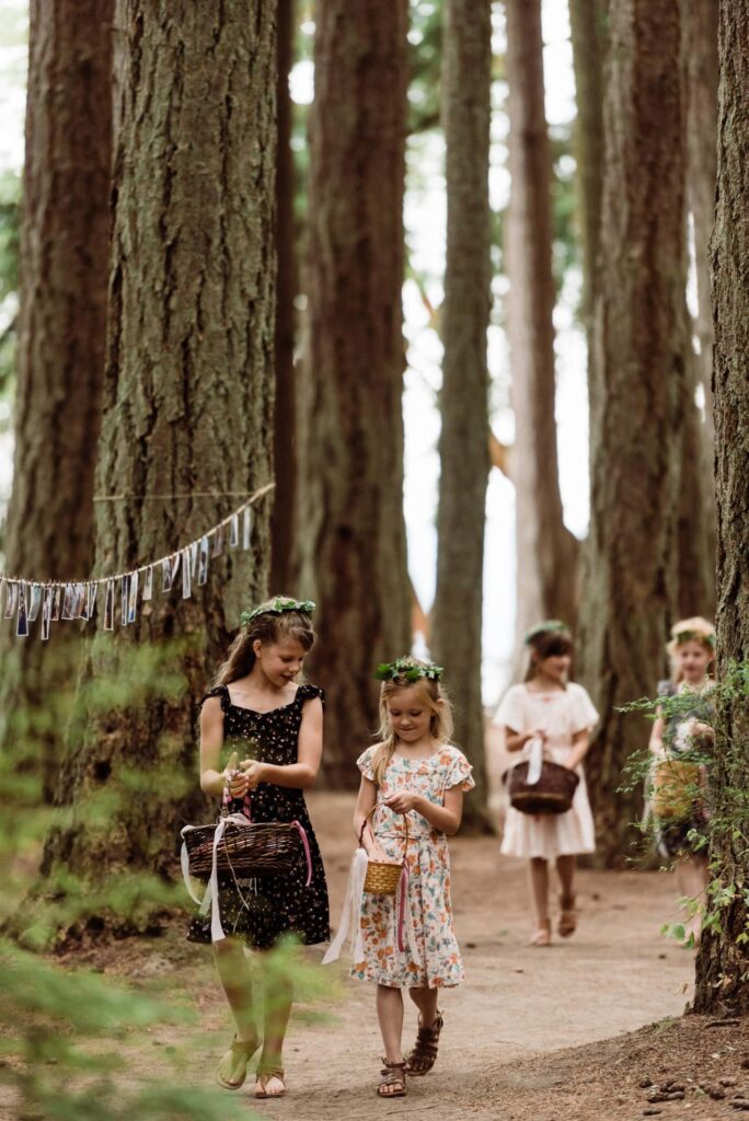 Flower girls walking down a woodland trail during a Pacific Northwest elopement.