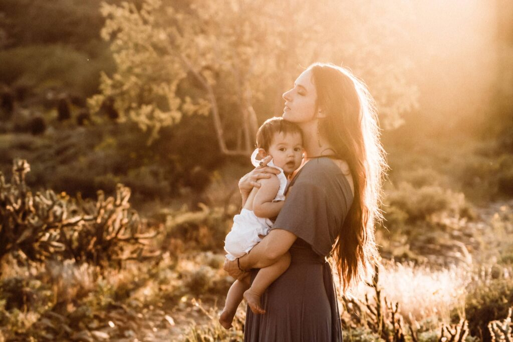 Mother holding her infant during a sunset family photography session.